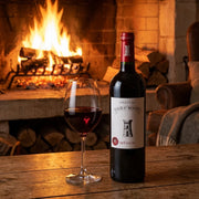 2016 Chateau Tour St. Bonnet - Medoc (750ml) | This wine and a wine glass by a roaring fire