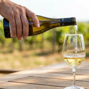 2024 Samuel Billaud - Chablis Grand Terroir (750ml) [PRE ARRIVAL] | This wine being poured into a glass. elongate the neck of the bottle and add a hand that is pouring the bottle.