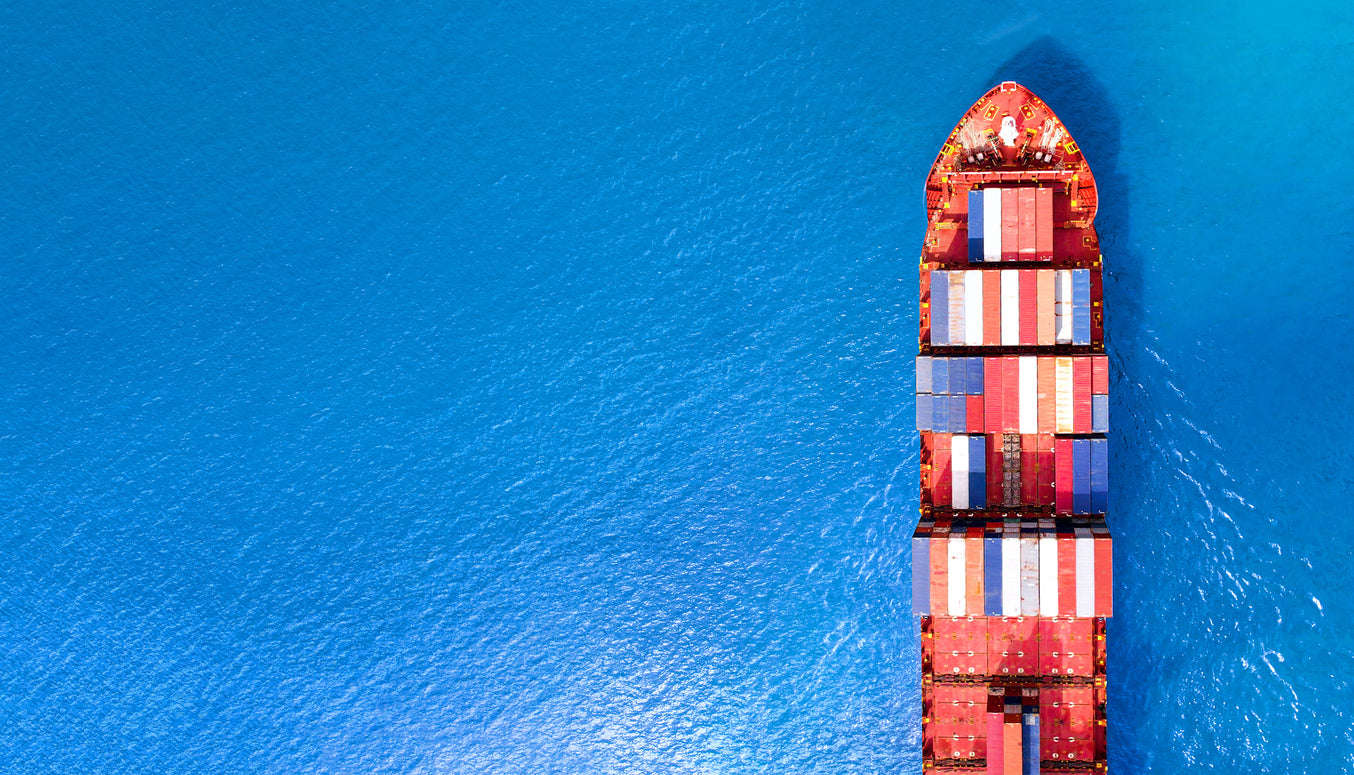 Container ship with red and blue containers sailing on a blue ocean